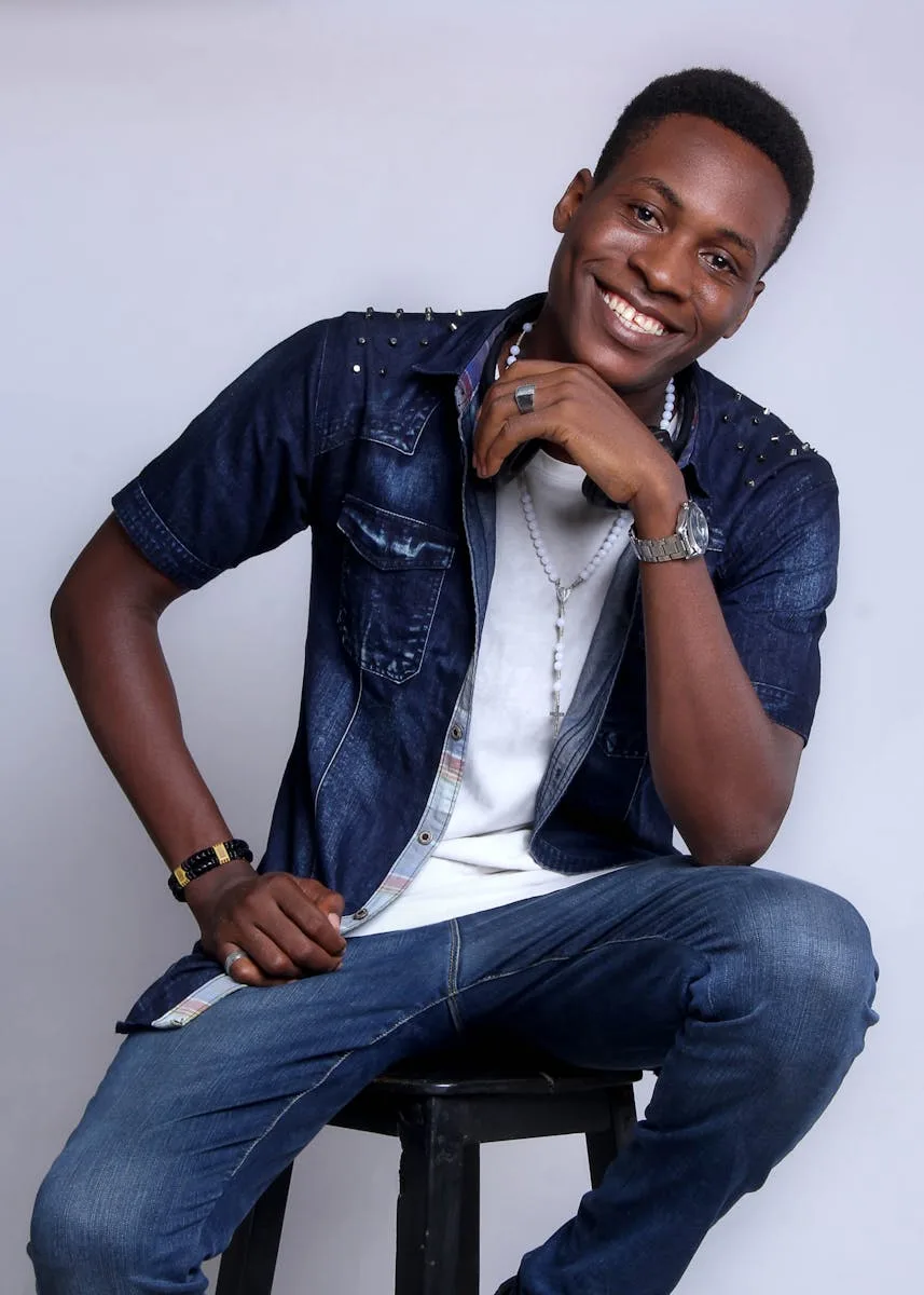 Young adult smiling indoors in casual denim outfit, exuding relaxed style.